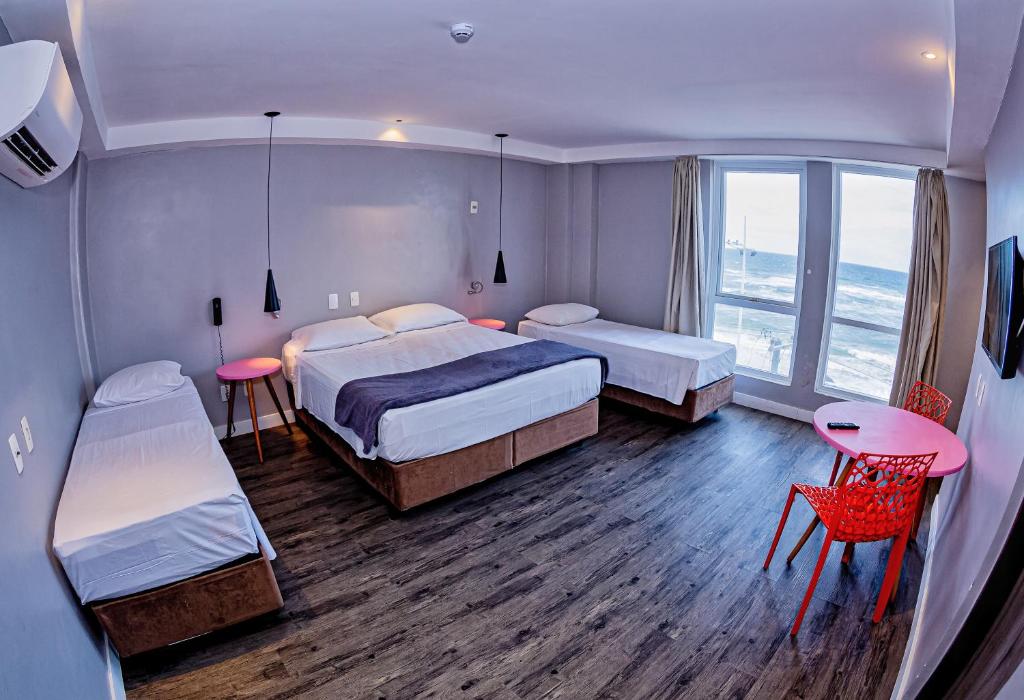 萨尔瓦多B酒店的酒店客房带两张床和一张桌子以及椅子。