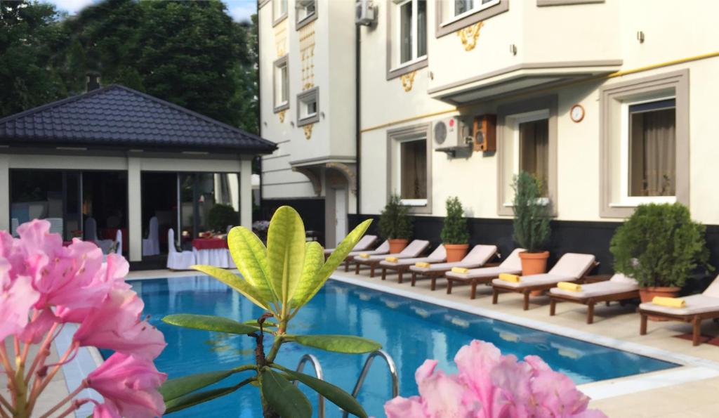 利沃夫Eney Boutique Hotel的酒店设有带椅子和粉红色鲜花的游泳池