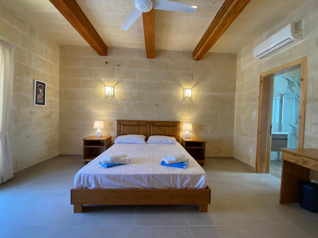 萨奈特Ta' Ganna Farmhouse的一间卧室配有带2个床头柜的床和吊扇