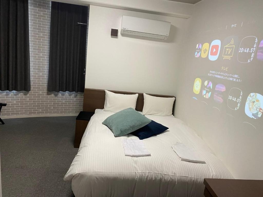 佐贺市TAPSTAY HOTEL - Vacation STAY 35238v的卧室配有白色床和绿色枕头