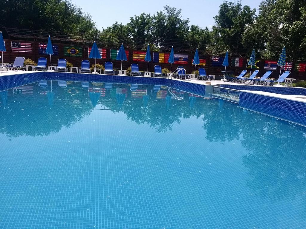 SlivekКъща за гости "Там край реката "的一个带椅子和蓝伞的大型游泳池