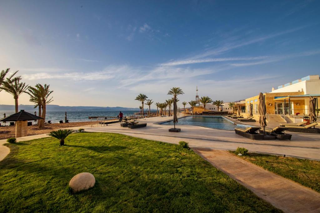 亚喀巴Luxotel Aqaba Beach Resort & Spa Only 15 years plus的拥有游泳池、棕榈树和海洋的度假胜地