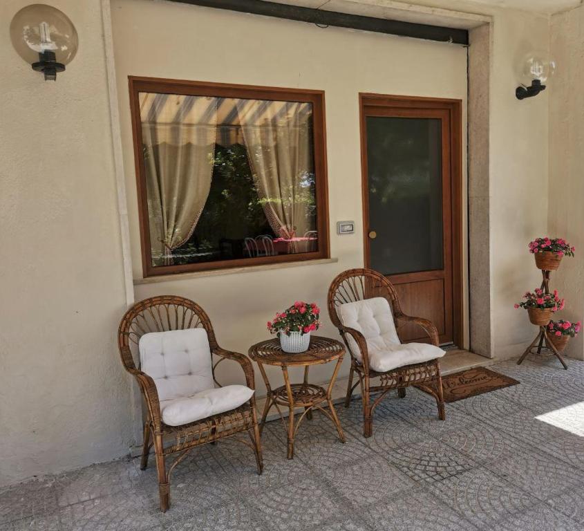 蒙蒂菲阿斯科尼Al Centesimo Chilometro - Ristoro del Pellegrino的庭院设有两把椅子、一张桌子和一扇窗户。