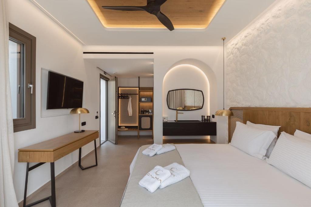 萨鲁Calma Suites Mykonos的一间卧室配有一张床、一张书桌和一台电视