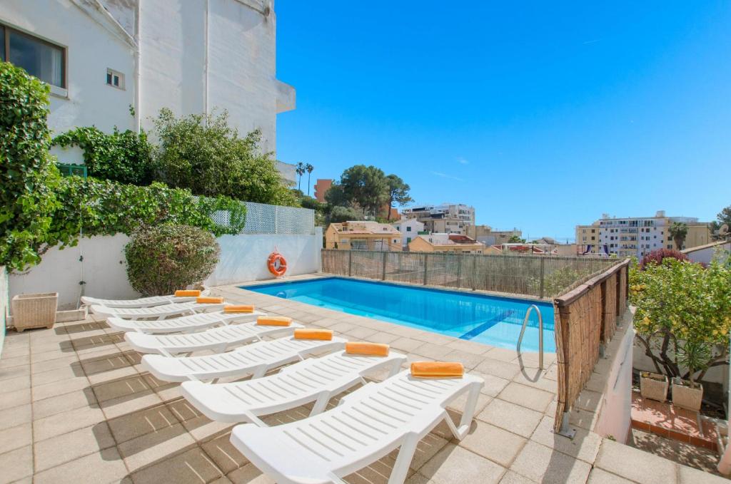 马略卡岛帕尔马YourHouse Ca Na Salera, villa near Palma with private pool in a quiet neighbourhood的游泳池旁的一排白色躺椅