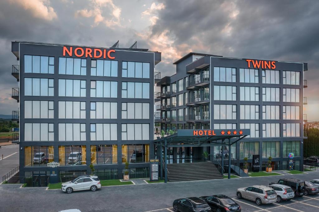 勒德乌齐Hotel Nordic Twins的停车场内有车辆的旅馆