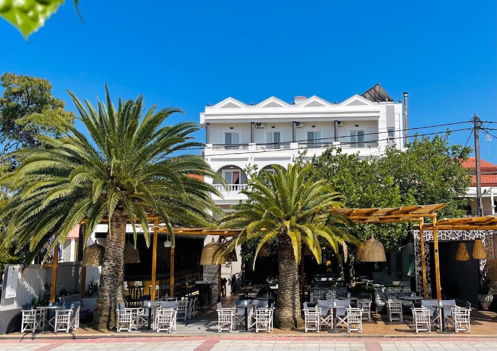 佩弗奇加里尼酒店的一座白色的建筑,种植了棕榈树,配有桌椅