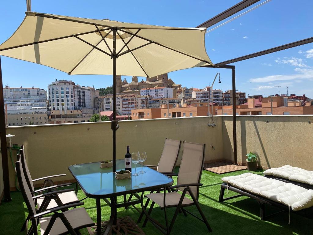 阿尔卡尼斯Apartamentos Alcañiz, Suite Deluxe的屋顶上配有遮阳伞的桌椅