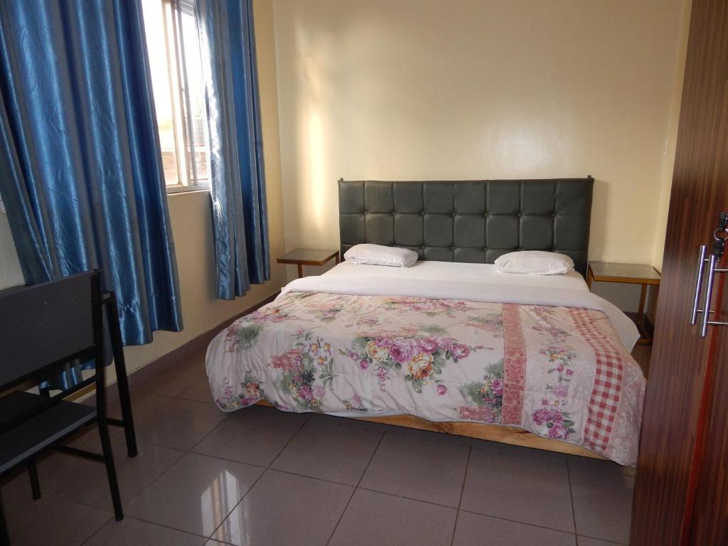 基加利SERENITAS Apartment的一间卧室配有一张带花卉床罩的大床