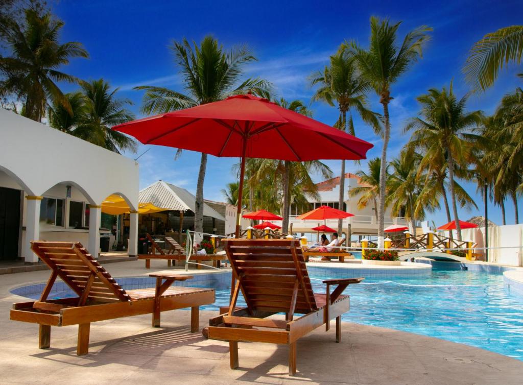 La Herradura巴伊亚德尔索尔酒店的一个带两把椅子和红伞的游泳池