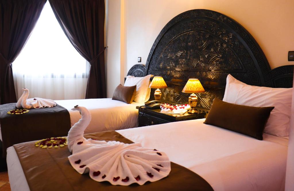 阿加迪尔Hôtel Riad Salam Agadir的酒店客房设有两张床,一张桌子上有一个天鹅