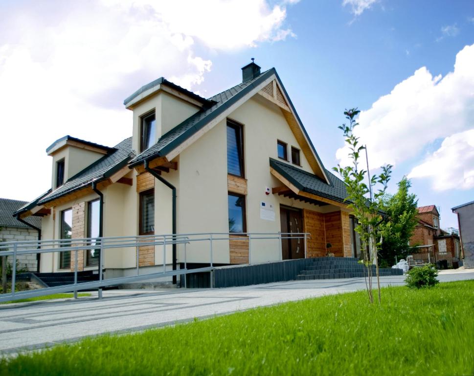 扎莫希奇舒适别墅的一座带门廊和绿草的房屋