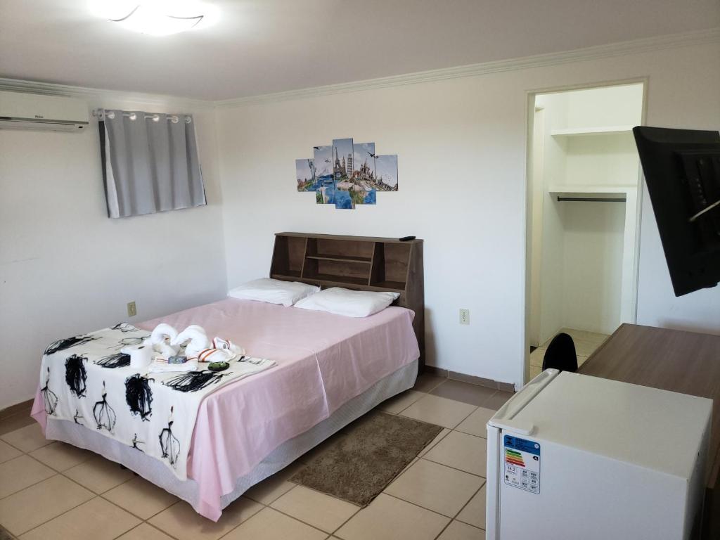 瓜拉派瑞Enseada Suítes的一间卧室配有一张带粉色毯子的大床