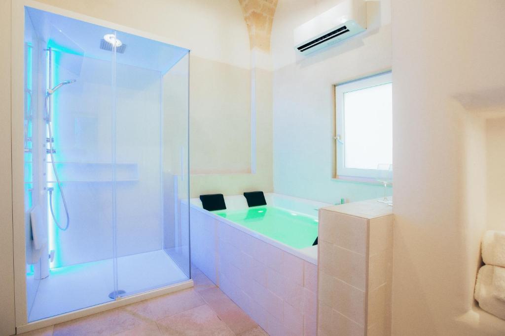 布林迪西Filia Solis - Old Town SUITEs & SPA的带浴缸和玻璃淋浴间的浴室。