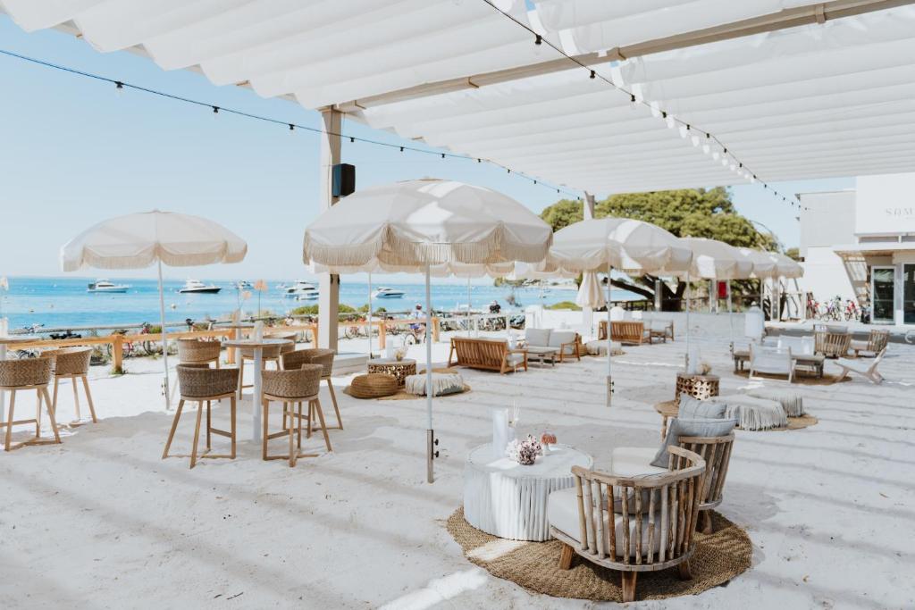 罗特内斯特岛Samphire Rottnest的海滩上设有桌椅和遮阳伞的餐厅
