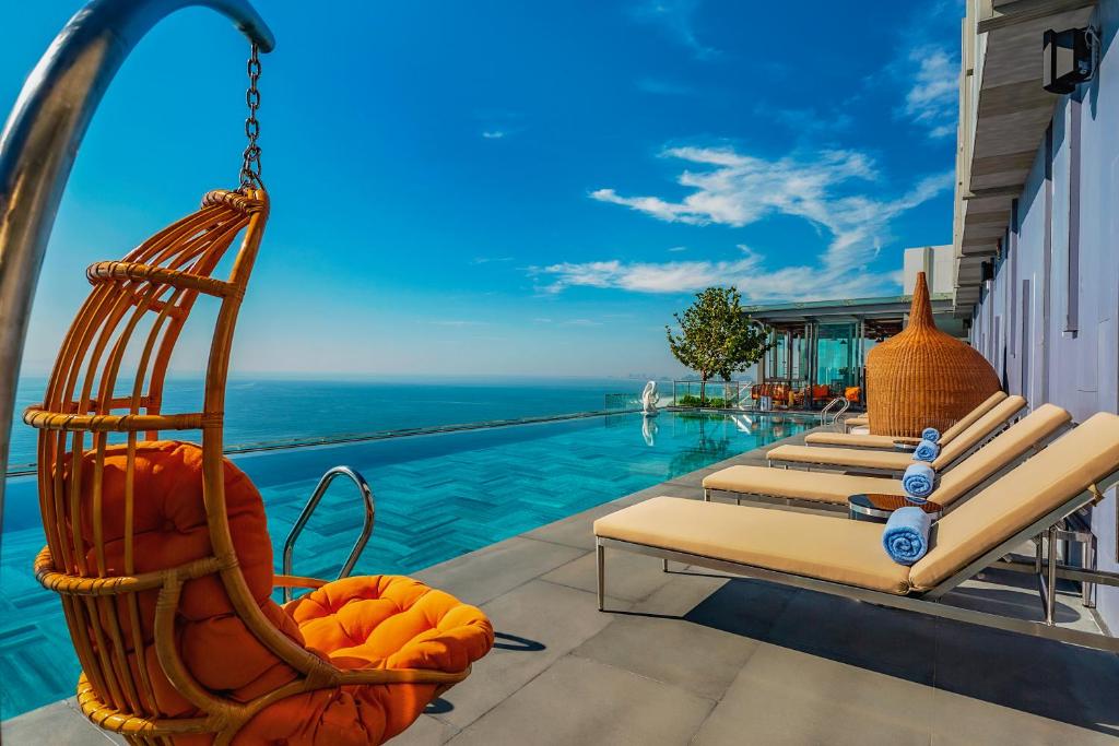 岘港Le Sands Oceanfront Danang Hotel的一个带躺椅的度假游泳池和大海