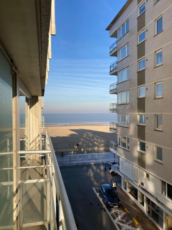 克诺克－海斯特bel appartement à 100m de la plage的从带停车场的大楼的阳台上可欣赏到风景