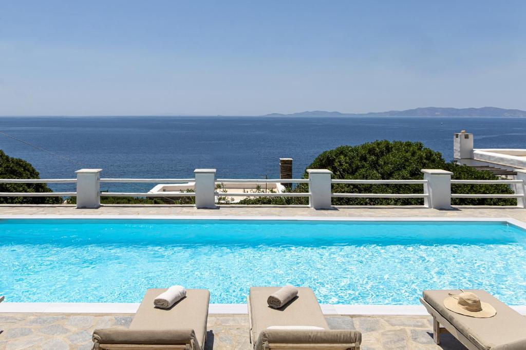 基奥尼亚Big Blue Suites & Apartments的一个带2把躺椅的游泳池和海洋