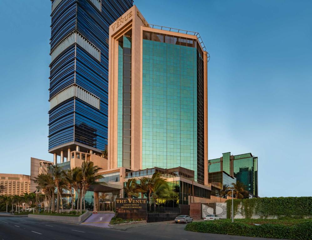 吉达The Venue Jeddah Corniche的一条街道前方有棕榈树的高楼