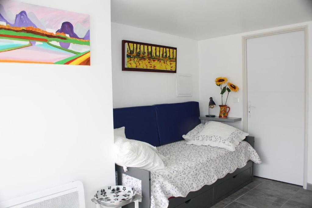 科隆比耶尔studio soleil的卧室配有一张床,墙上挂有绘画作品