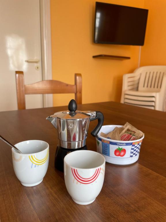 里贝拉Accogliente Appartamento Costa Makauda的茶壶和桌子上的两个杯子