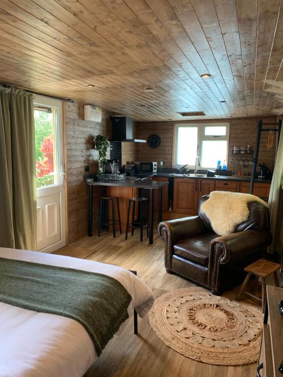 朗塞斯顿1 bedroom woodland cabin的一间卧室配有一张床和一把椅子,一间厨房