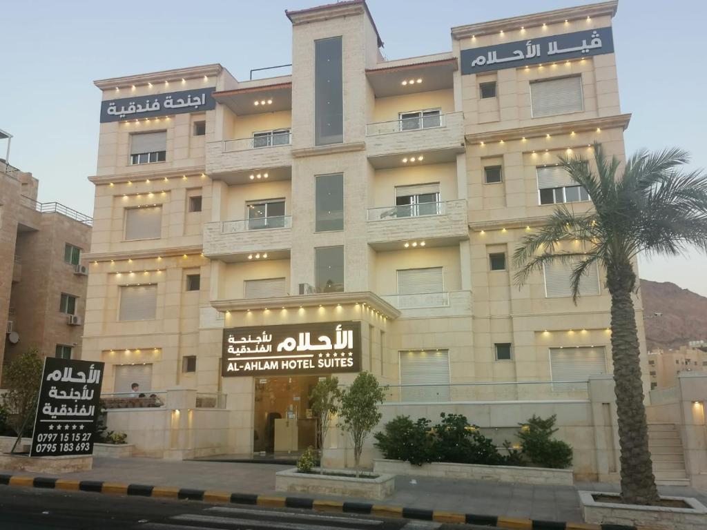 亚喀巴Al-Ahlam Hotel Apartments的前面有棕榈树的建筑