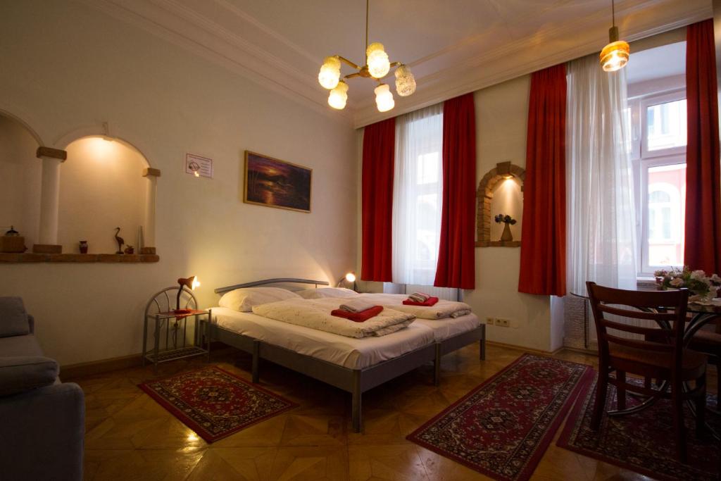 维也纳快乐旅馆的一间设有床铺的卧室,位于一间设有红色窗帘的房间
