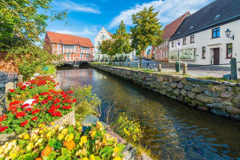 维斯马Ferienwohnungen im Gewölbe的花卉和建筑物的城镇河流