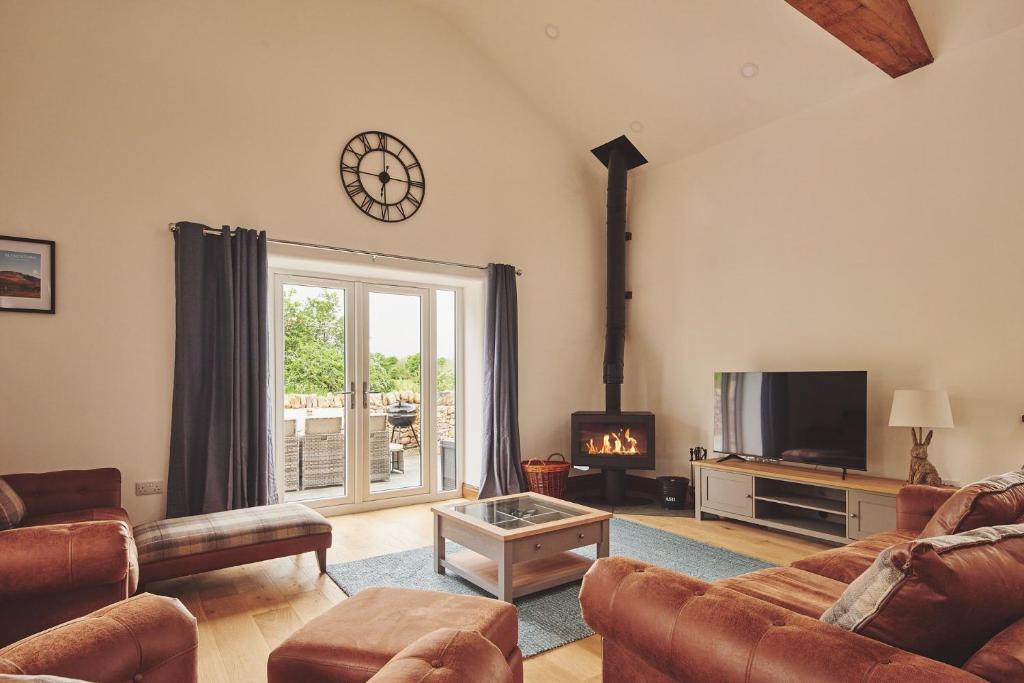 阿普比Plum Cottage的客厅配有沙发和墙上的时钟