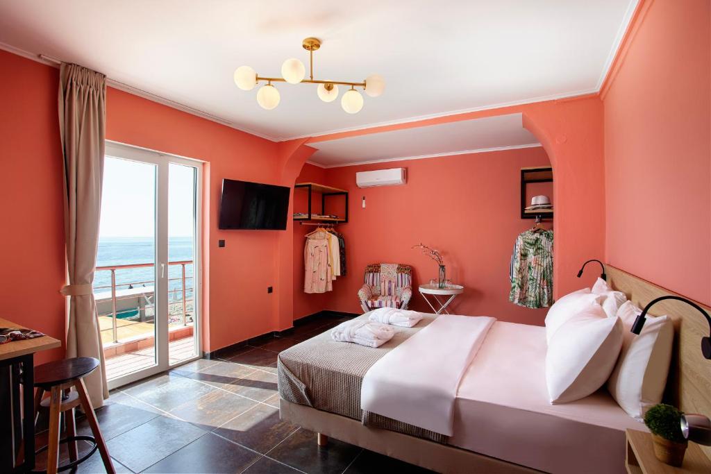 帕拉利亚卡泰里尼斯CONTE CRISTO Suites的一间卧室设有橙色的墙壁、一张床和一个阳台