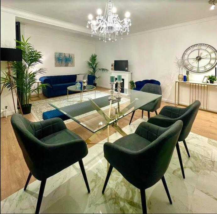 伦敦Luxury 3 bedroom 3 and a half bathroom flat in Swiss Cottage的客厅配有玻璃桌和绿色椅子