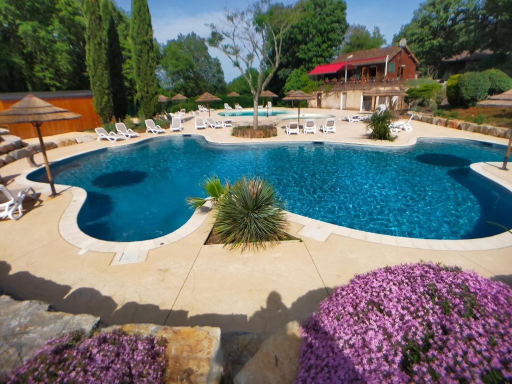 圣锡尔克－拉波皮la Truffière Saint Cirq Lapopie的一个带椅子和紫色花卉的大型游泳池