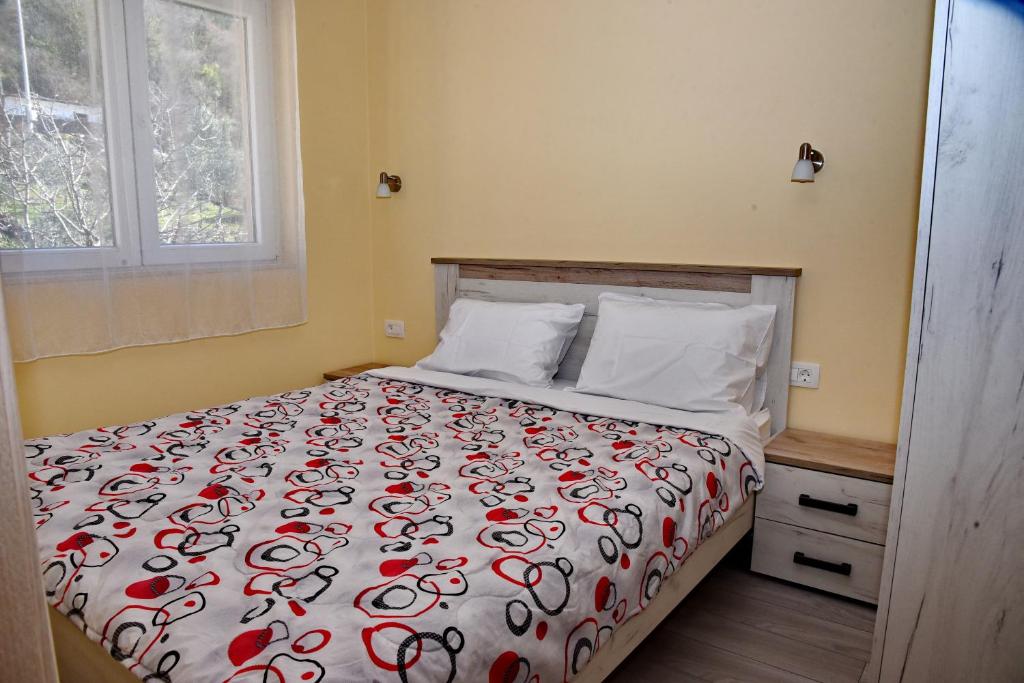 科托尔Sunset Apartments的一间卧室配有一张带红色和白色棉被的床