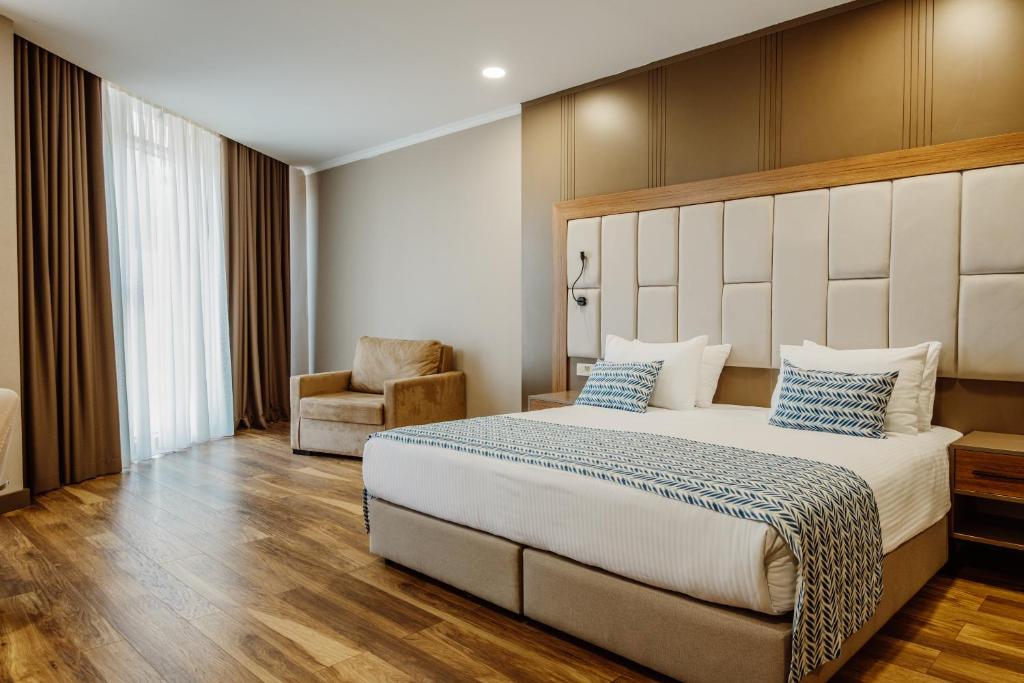 巴统King Solomon Batumi Hotel的一间卧室配有一张大床和一把椅子