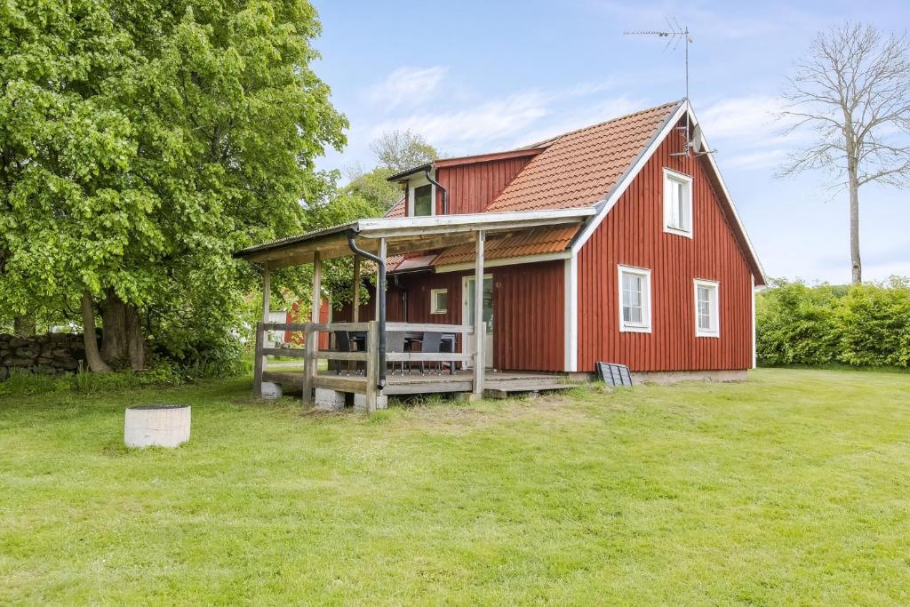 永比Cozy cottage at Bolmstad Sateri by Lake Bolmen的一个带门廊和院子的红色谷仓