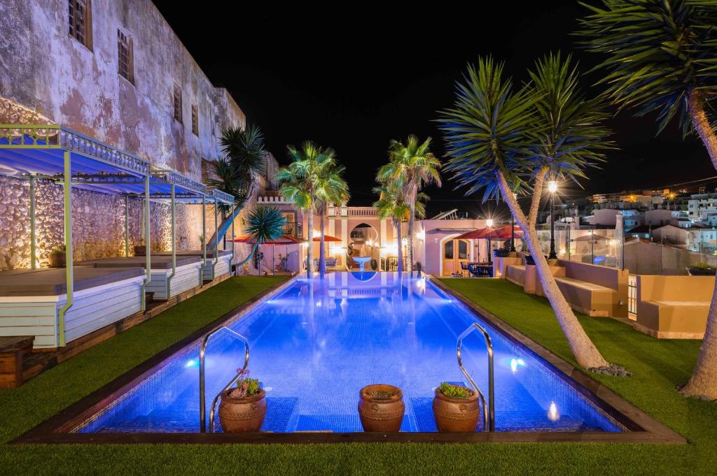 阿尔布费拉Vila Origens Boutique Hotel Albufeira – Adults Only的棕榈树和建筑的夜间游泳池