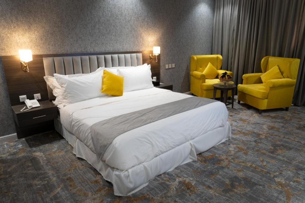 泰布克فندق دبليو اس ws的一间卧室配有一张大床和两张黄色椅子
