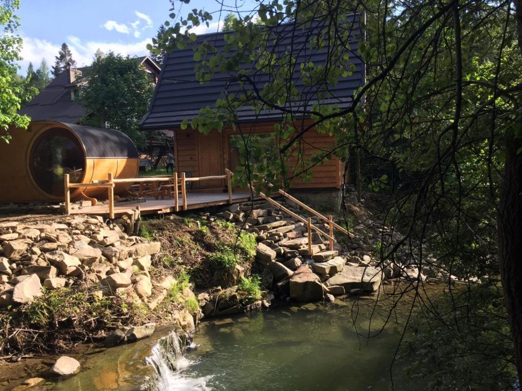 ŻabnicaChatka z sauną nad rzeką的一座小木屋,设有一座河上桥梁