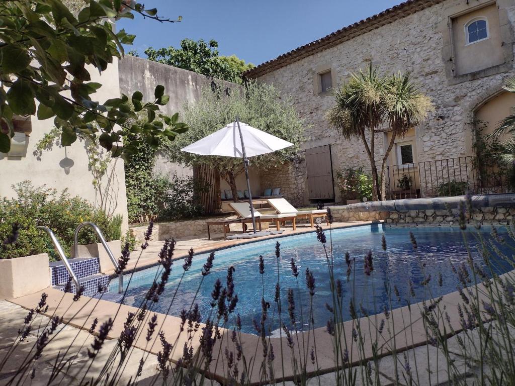 Saint-Géniès-de-MalgoirèsLa Maison Des Autres, piscine chauffée, chambres d'hôtes proches Uzès, Nîmes, Pont du Gard的一个带桌子和遮阳伞的游泳池