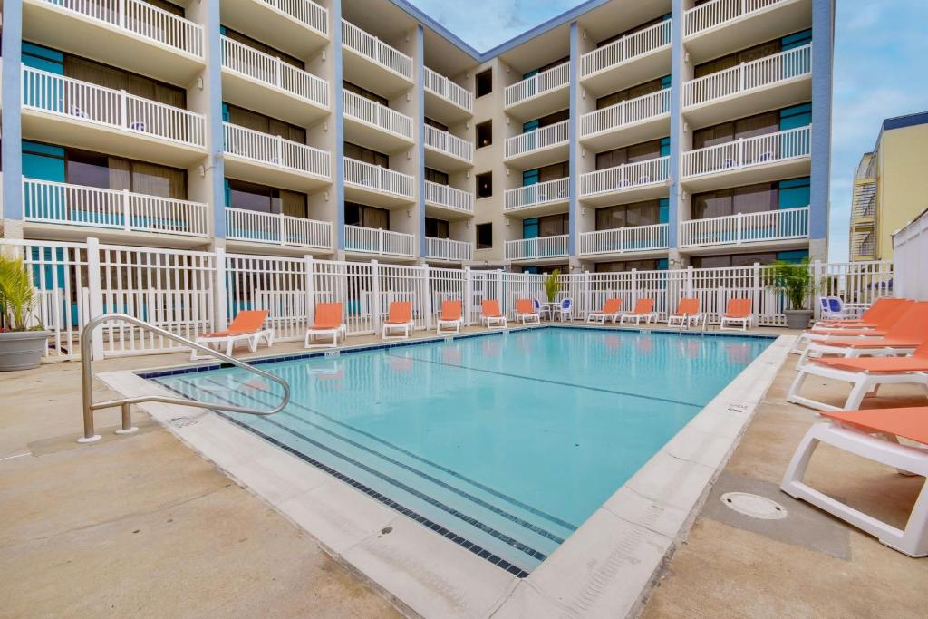 大洋城卡萨布兰卡海滨酒店的酒店前的游泳池配有橙色椅子