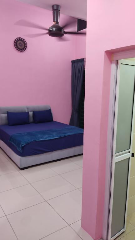 浮罗山背PRESTIJ H0MESTAY的粉红色客房内的一张床位,配有吊扇