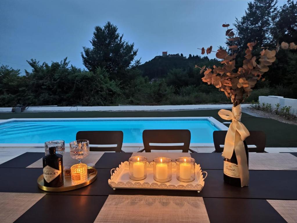 锡尼Kuća za odmor Sika的一张桌子,上面放着蜡烛和葡萄酒瓶,还有一个游泳池