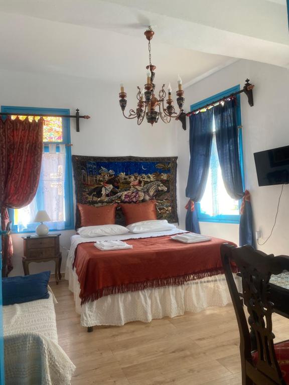 干尼亚DIONI的一间卧室配有一张带红色床单和蓝色窗帘的床