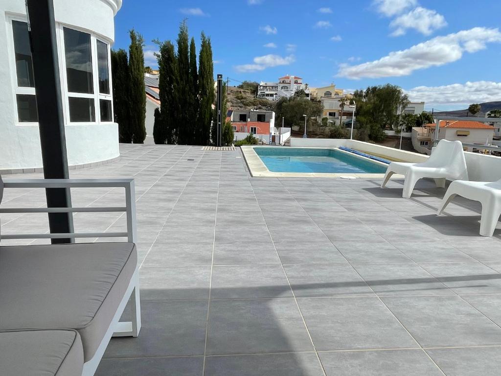 塔拉哈勒赫Villa Neila, Fuerteventura的一个带白色椅子的庭院和一个游泳池