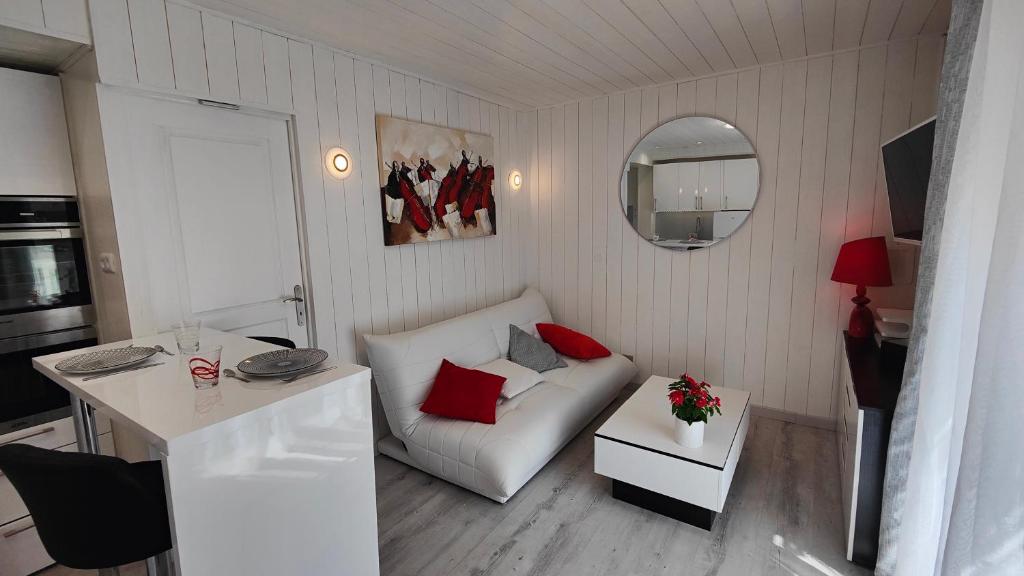 布里夫拉盖亚尔德Le Petit Paradis的一间小客厅,配有白色的沙发和红色的枕头