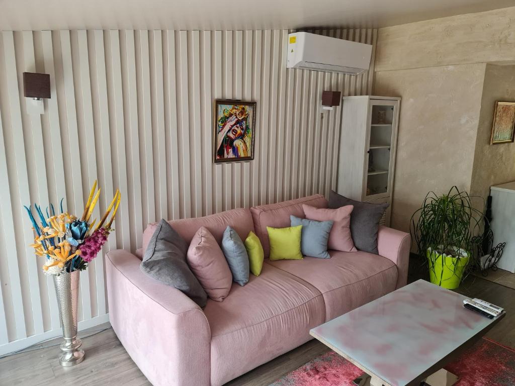 斯利文GRANDE SPA DELUXe STUDIOS的客厅配有粉红色的沙发及色彩缤纷的枕头