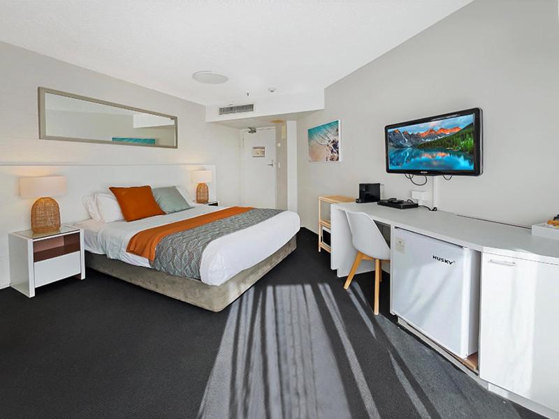 马库拉Seaside Stays Marcoola Private studio 2515的酒店客房配有一张床和一张书桌及一台电视