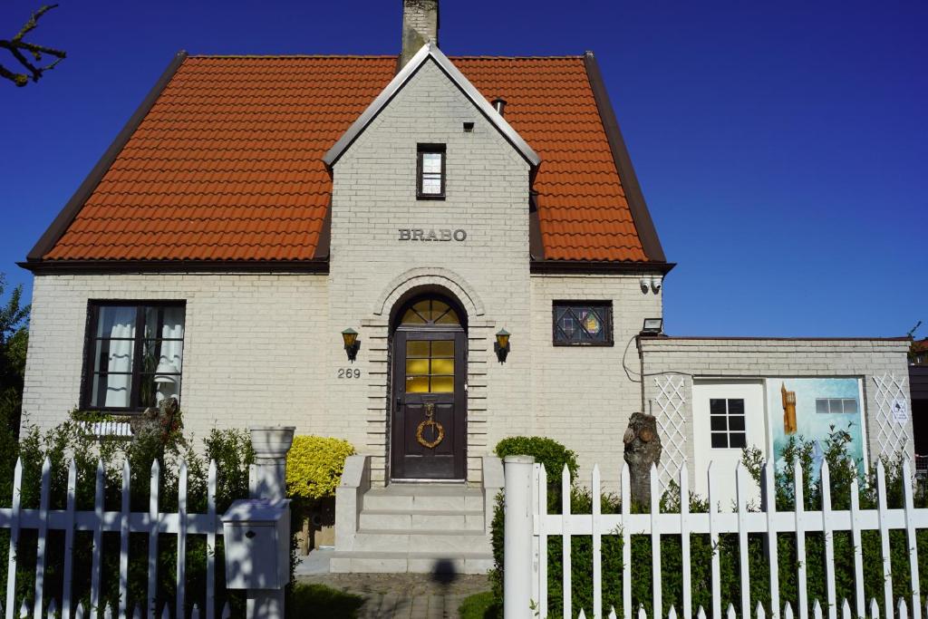 兰斯克鲁纳BRABO的白色的房子,有橙色的屋顶和白色的围栏