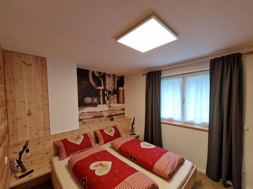 塞纳莱斯Ferienwohnung Schnalstal " Die Schneiderei "的一间卧室配有一张带红色枕头的床和一扇窗户